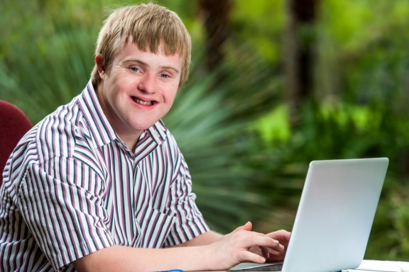 Young man with Downs Syndrome on laptop