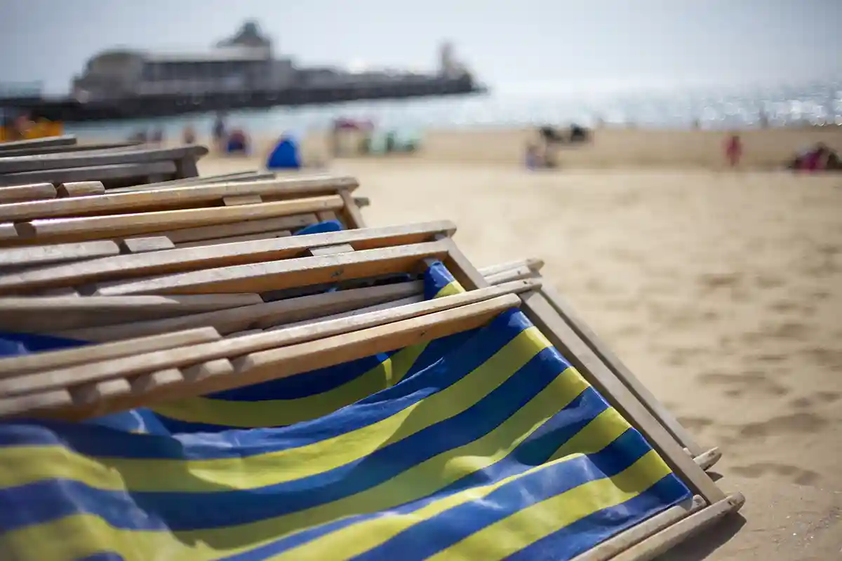 Deckchairs on Bournemouth beach with pier in the background.